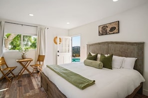 A bedroom with a bed, a view of a pool, and a door leading outside.