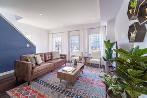 Ein Wohnzimmer mit braunem Ledersofa, einem Couchtisch und gemusterten Teppichen.