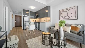 Una sala de estar moderna con un sofá gris, una mesa de centro y una zona de comedor con una mesa y sillas blancas.