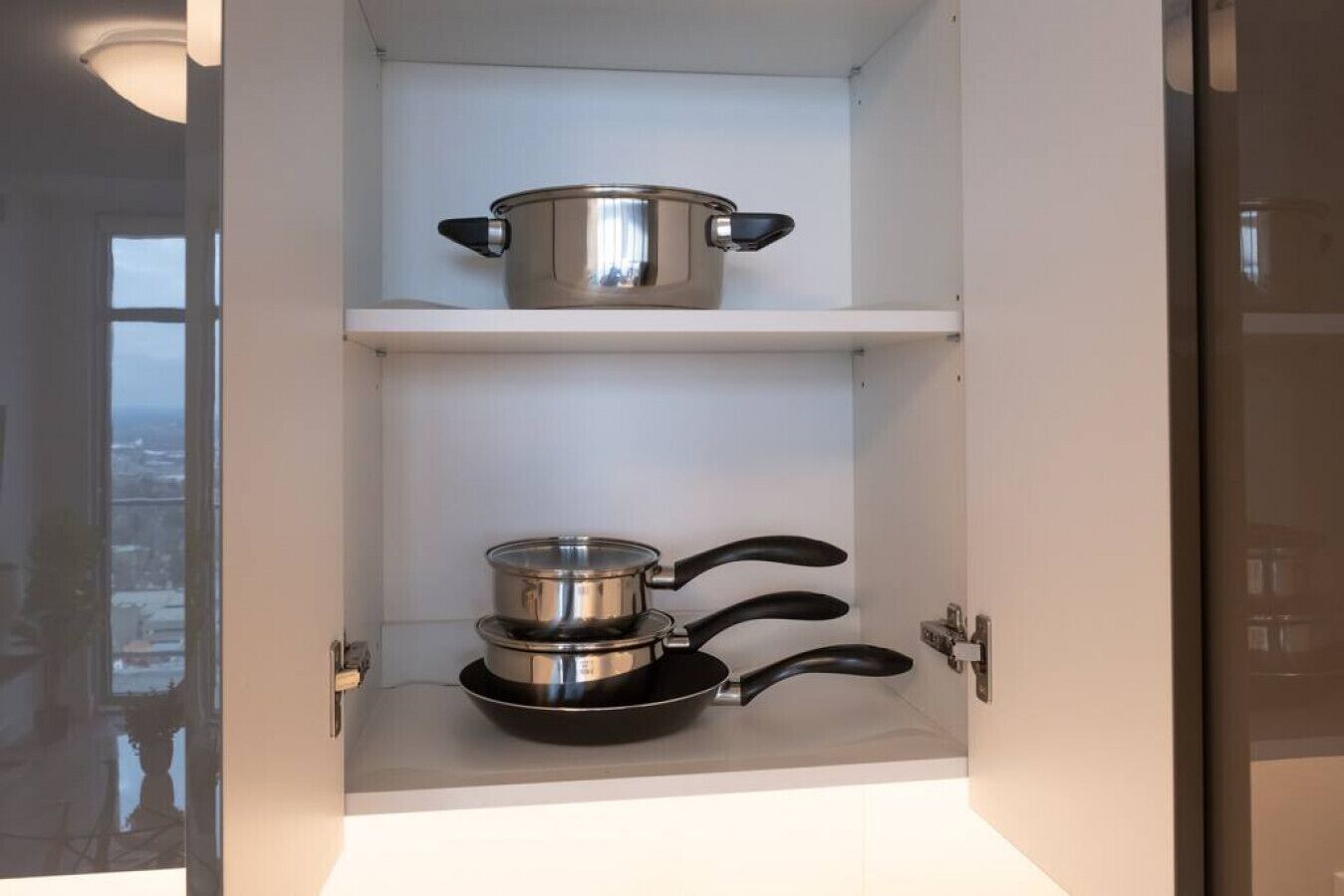 A kitchen with a pot on the upper shelf and a pan on the lower shelf.