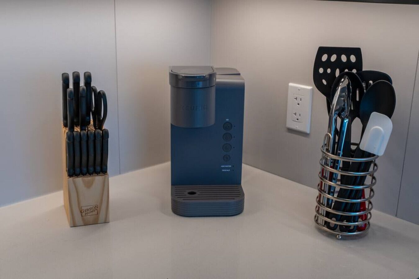 Un piano di lavoro in cucina con una macchina per il caffè, un portacoltelli e un contenitore per utensili.