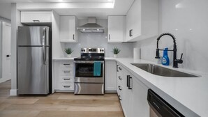 A modern kitchen with stainless steel appliances, white cabinetry, and a black dishwasher. - Bright & Cozy 1BR Basement Unit (Kitchener)
