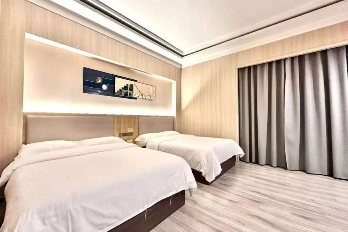 Une chambre d’hôtel avec deux lits, une grande fenêtre avec des rideaux et une œuvre d’art accrochée au mur.