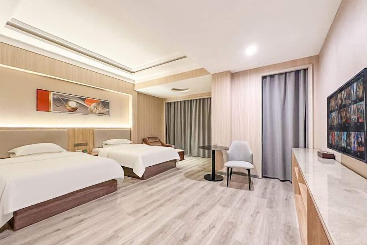 A hotel room with two beds, a desk, and a chair.