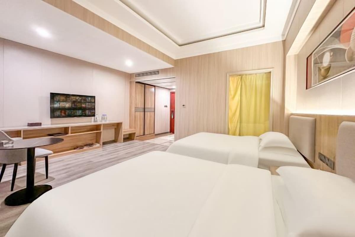 A modern hotel room with a large bed, a small table, a TV, and a desk.