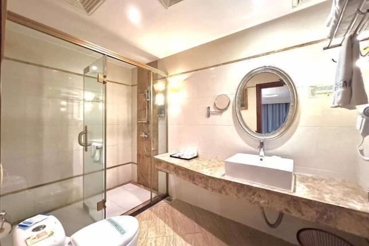 A bathroom with a glass shower enclosure, a sink with a vanity mirror, and a toilet.