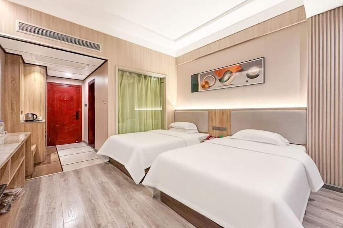 A hotel room with two beds, a desk, and a bathroom.