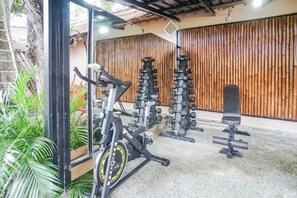 Un gimnasio con equipo de ejercicio, incluyendo una prensa de banca, mancuernas y una bicicleta estática.