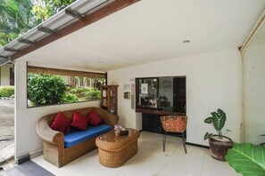 Una habitación con un sofá, una mesa de centro, un televisor y una planta grande en maceta.