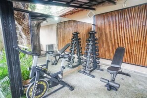 A gym with exercise equipment, a bench, and a wooden wall. - Kampung 168 Jimbaran Bali (Bali)
