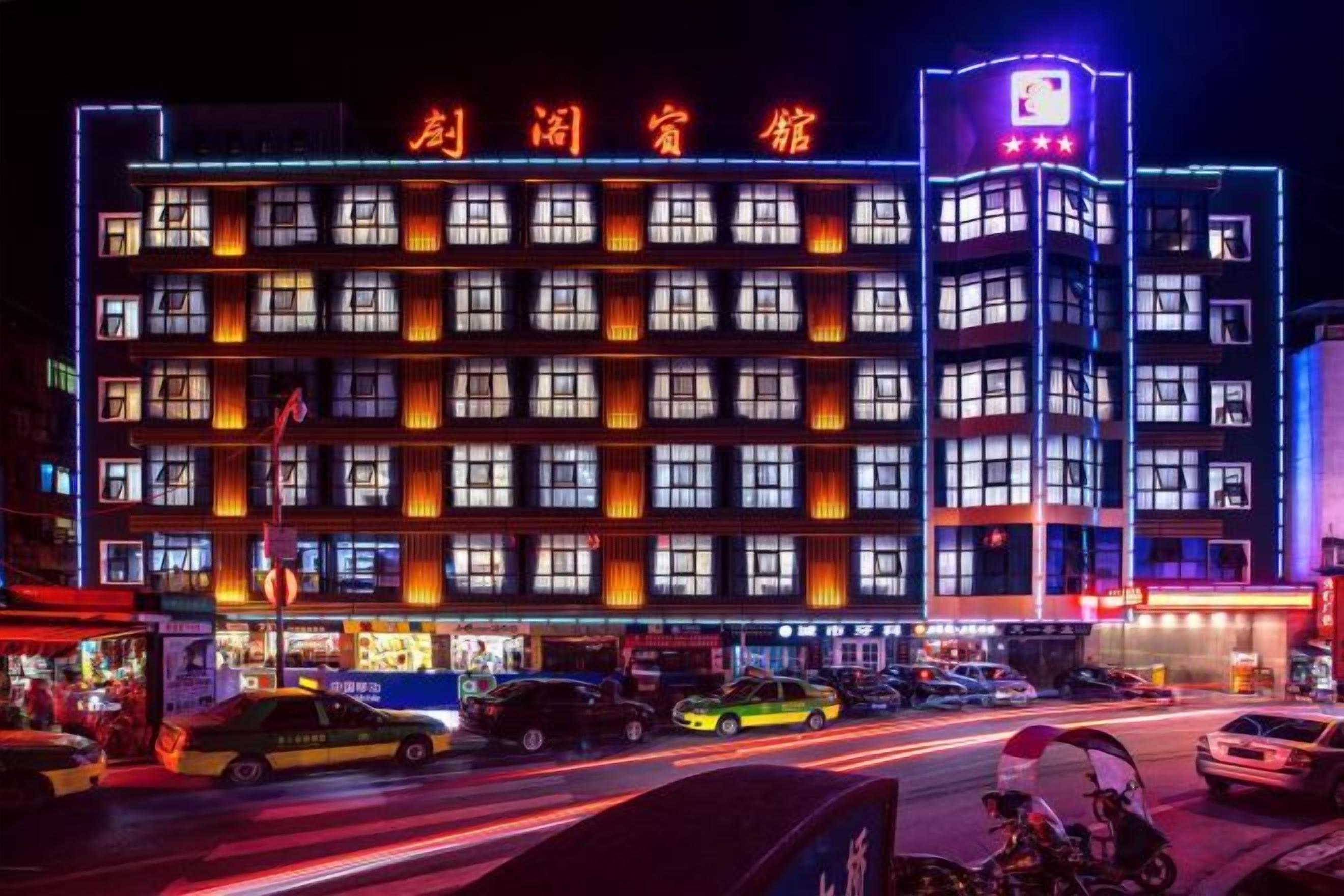 A multi-story hotel with a prominent sign, multiple floors, and a variety of vehicles in front.