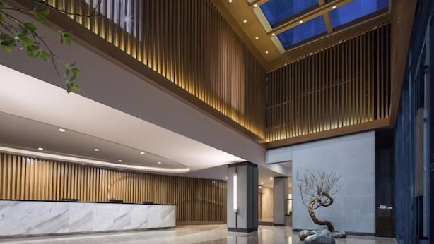 Un vestíbulo amplio con un mostrador de recepción, un tragaluz grande y una decoración minimalista.