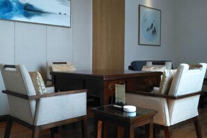 A modern room with a wooden desk, two chairs, a small table, and artwork on the walls.
