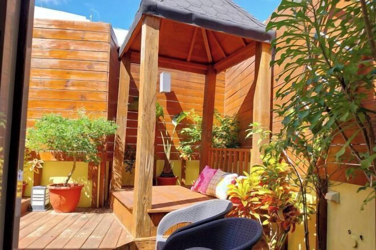 A wooden deck with a covered seating area, potted plants, and a small table.