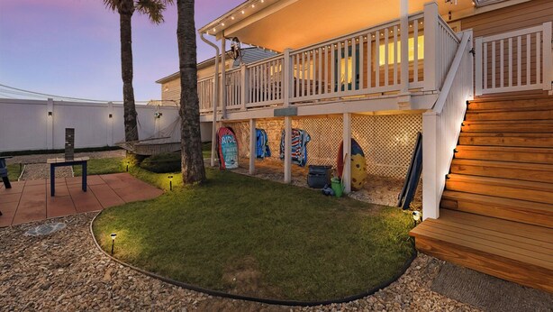 Ein zweigeschossiges Haus mit überdachter Terrasse, Holzterrasse und kleinem Rasen.