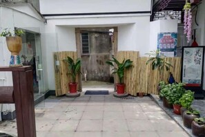 A courtyard with a tiled floor, bamboo fencing, and potted plants. - Xujia Tingyuan Inn (Suzhou)