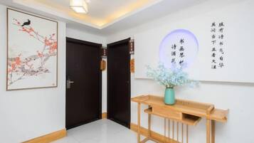 A hallway with a wooden console table, a framed artwork, and a wall with calligraphy.