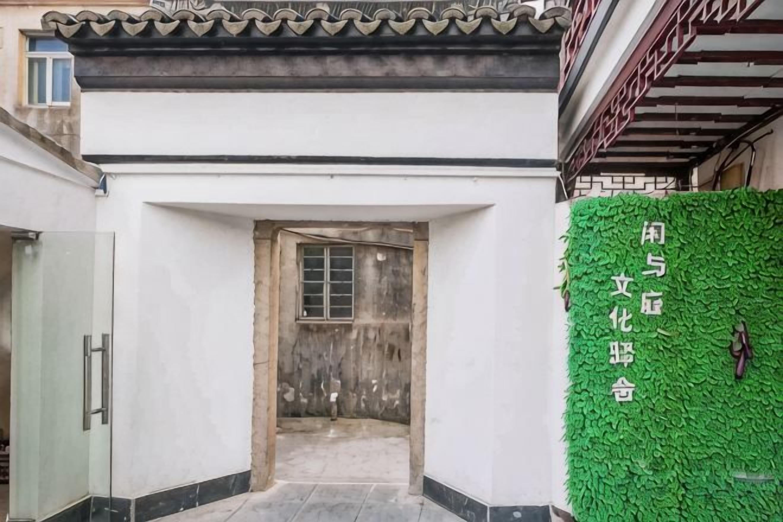 Ein traditioneller Hauseingang mit einer Holztür und einer grünen Wand mit chinesischen Schriftzeichen.