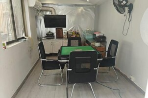 Una habitación pequeña con una mesa, sillas, un televisor y un ventilador.