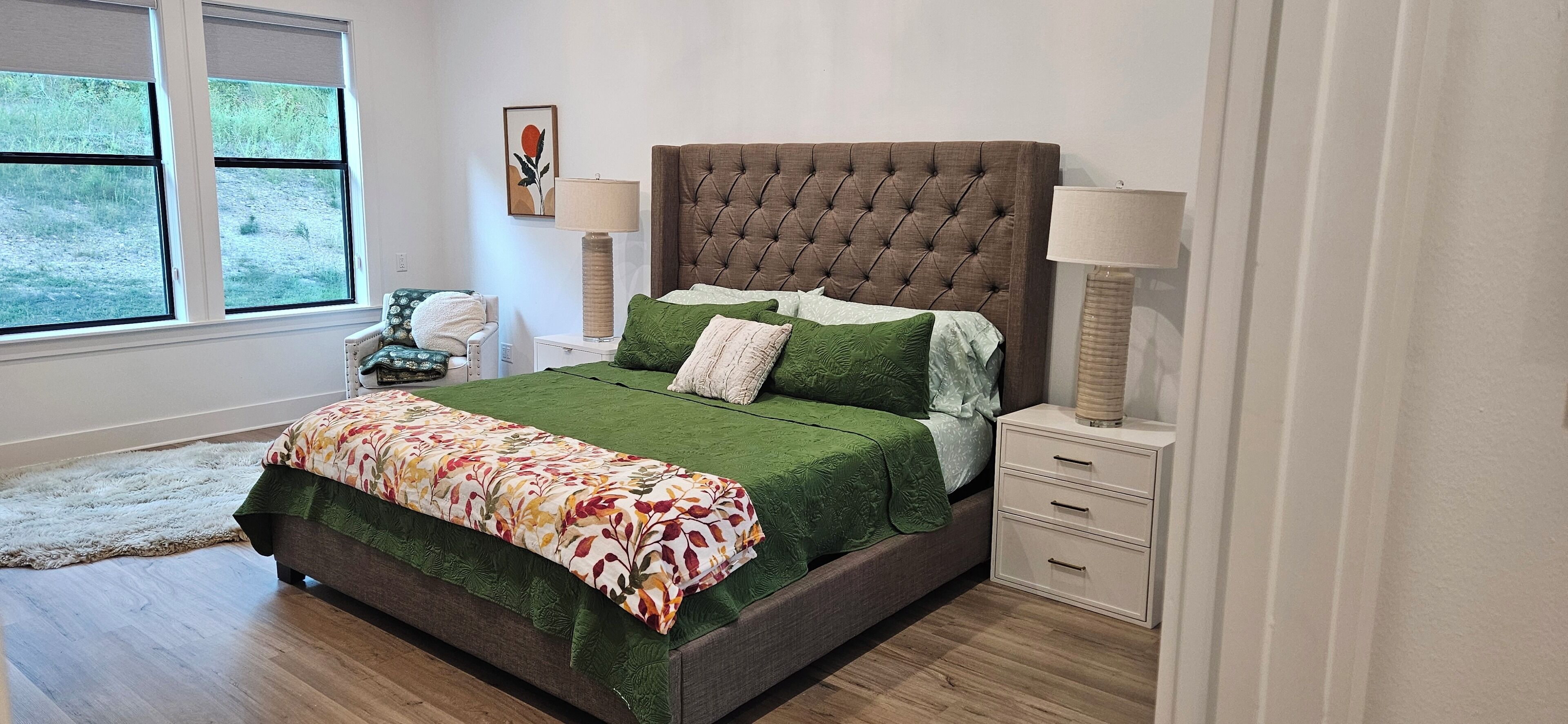 Une chambre avec un grand lit, deux tables de chevet, une fenêtre et un tapis.