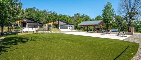 A residential property with a well-maintained lawn, a covered outdoor seating area, and a garage.