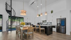 Cocina moderna con una isla central, armarios blancos y un refrigerador de acero inoxidable integrado.