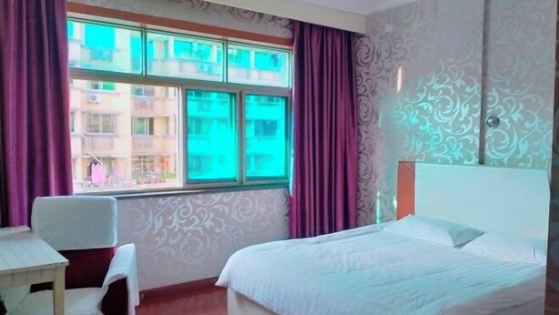 Een hotelkamer met een bed, een stoel, een tafel en een raam met gordijnen.