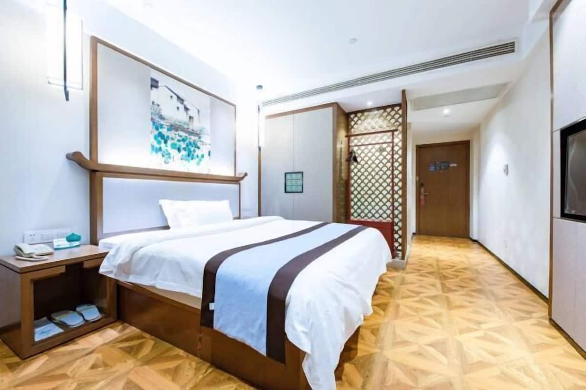 A hotel room with a bed, bedside table, and a large window.