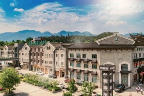 A hotel with traditional architecture, a parking area, and a mountainous backdrop. - Four Seasons Qingteng Garden Hotel (Xikou Chiang's Hometown) (Ningbo)