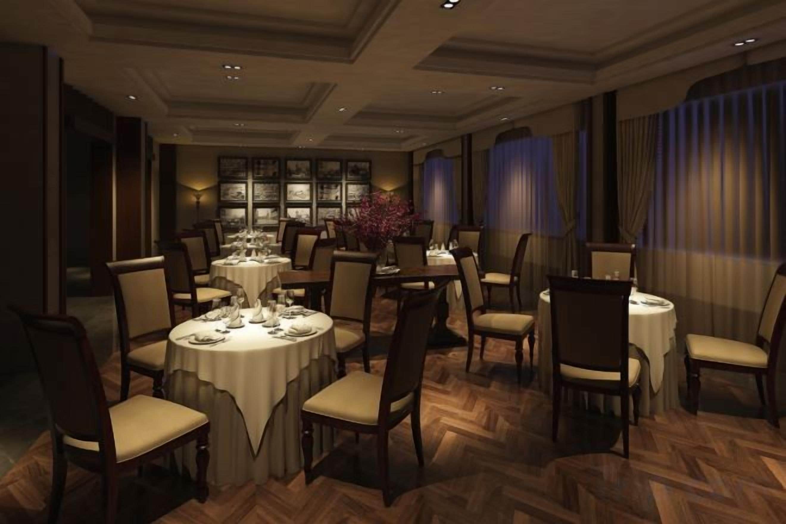 A formal dining room with round tables, chairs, and a chandelier.