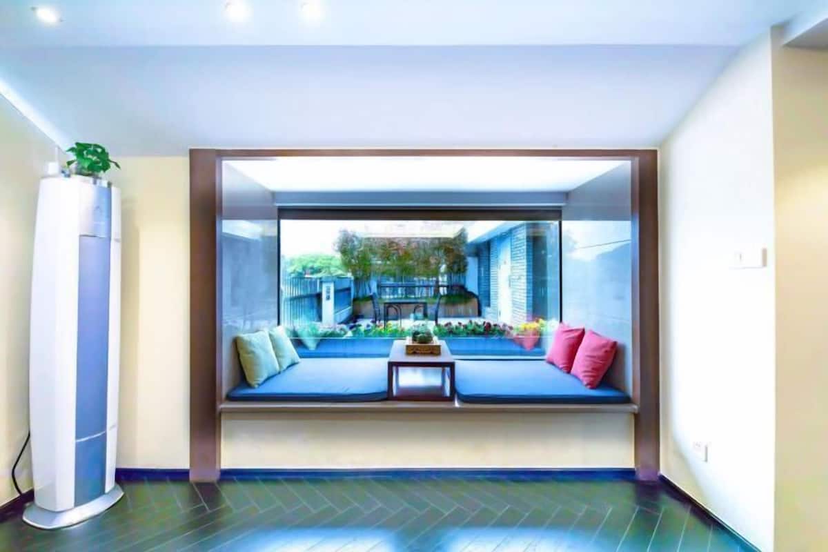 A room with a built-in window seat, a small table, and a potted plant.