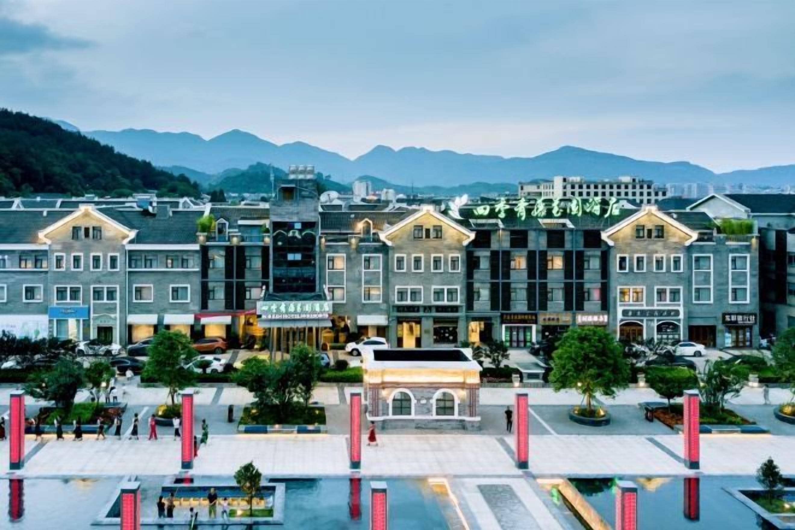 A hotel with a central courtyard, multiple floors, and a mountainous backdrop.