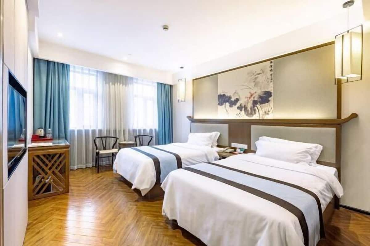 A hotel room with two beds, a desk, and a chair.