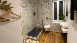 Une salle de bain moderne avec une douche à parois de verre, des toilettes blanches et un lavabo avec un miroir.