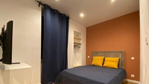 Une chambre à coucher avec un lit, une télévision, une armoire et un rideau.