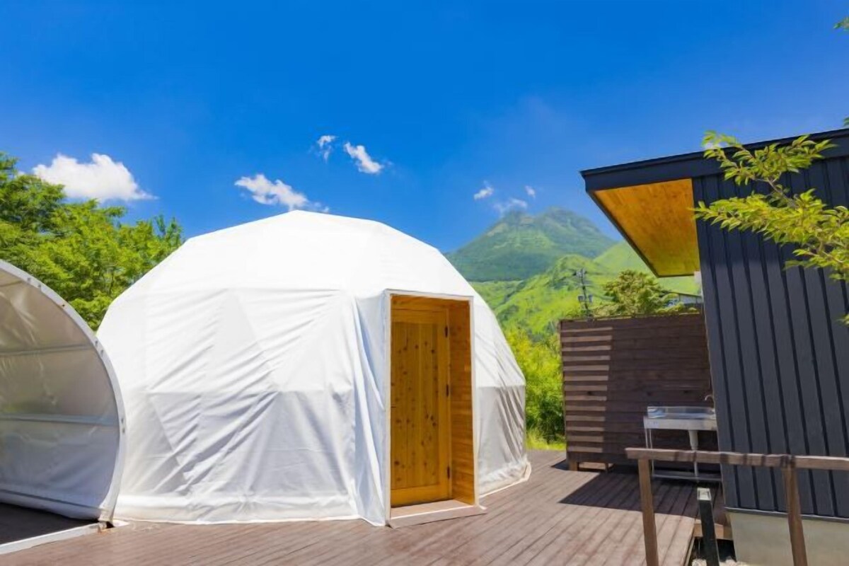 A white tent with a wooden door, a small wooden structure, and a wooden deck.