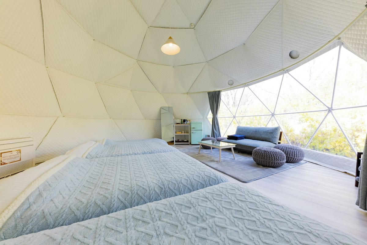 Una habitación amplia con una cama grande, una mesita pequeña y un sofá.