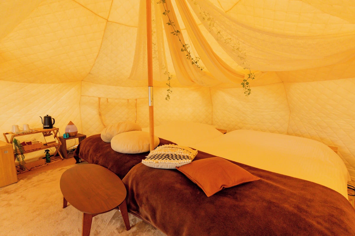 Una habitación tipo tienda de campaña con una cama, una mesita y una silla.