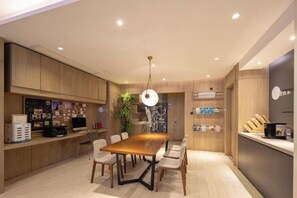 A modern kitchen with a wooden dining table, chairs, and a hanging light fixture. - HanTing Premium Hotel (Wuhan Huake University Innovation Street) (Wuhan)