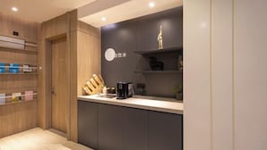 A modern kitchen with a dark countertop, wooden cabinets, and a coffee maker. - HanTing Premium Hotel (Wuhan Huake University Innovation Street) (Wuhan)