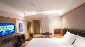A modern hotel room with a large bed, a flat-screen TV, a small round table, and a seating area with a sofa and chairs. - HanTing Premium Hotel (Wuhan Huake University Innovation Street) (Wuhan)
