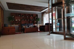 A spacious lobby with a wooden reception desk, a seating area with sofas, and a large glass door leading outside. - Wuxiang Greenrunpeng Express Hotel (Wuxiang)