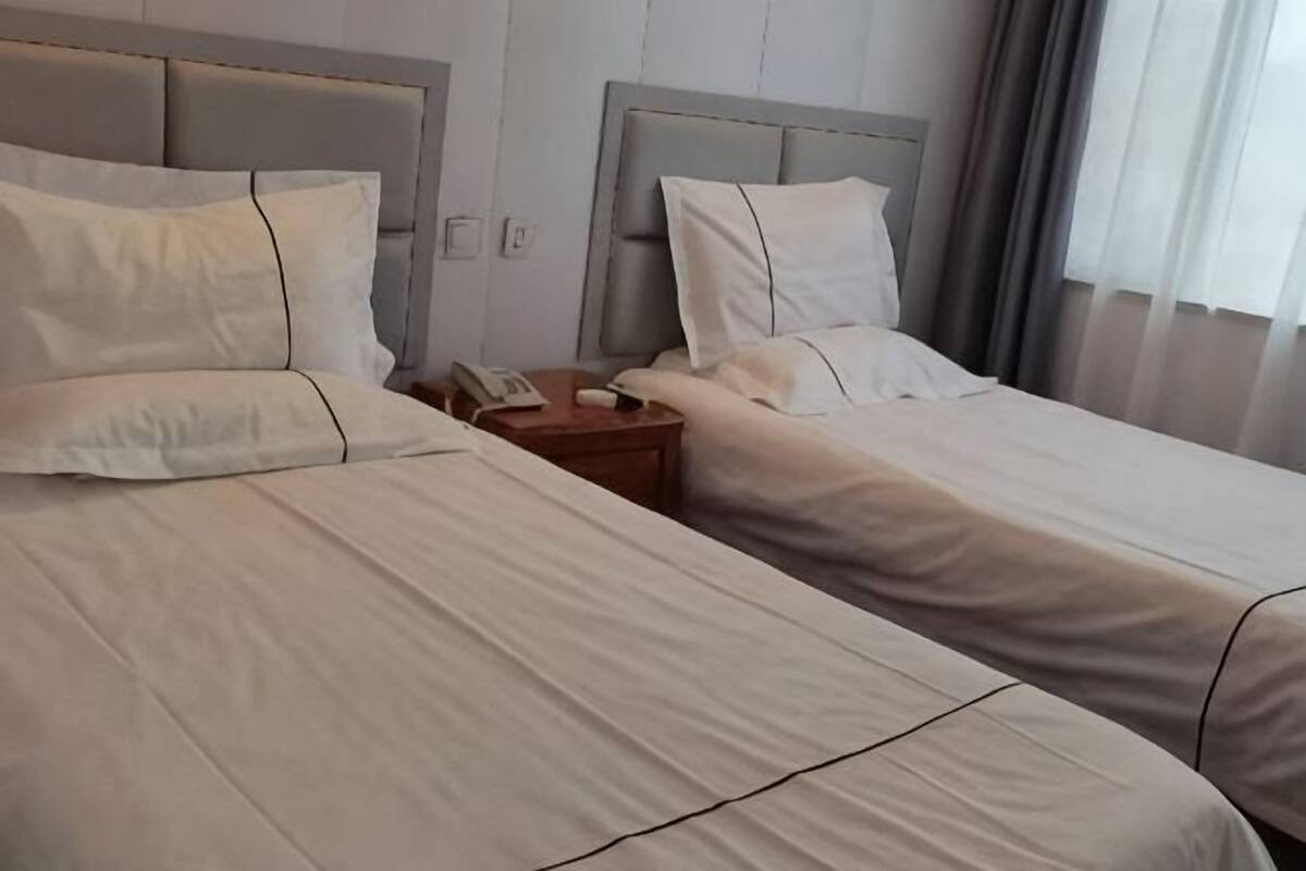 Een hotelkamer met twee bedden, een nachtkastje en een telefoon.