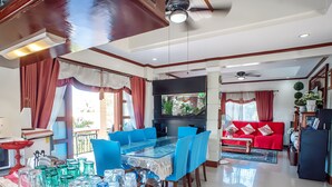 A spacious living area with a dining table, blue chairs, a red sofa, and a black entertainment unit. - Spacious 5-bedroom Panglao Home with FREE transfers, Infinity Pool, WiFi, & A/C (Panglao)