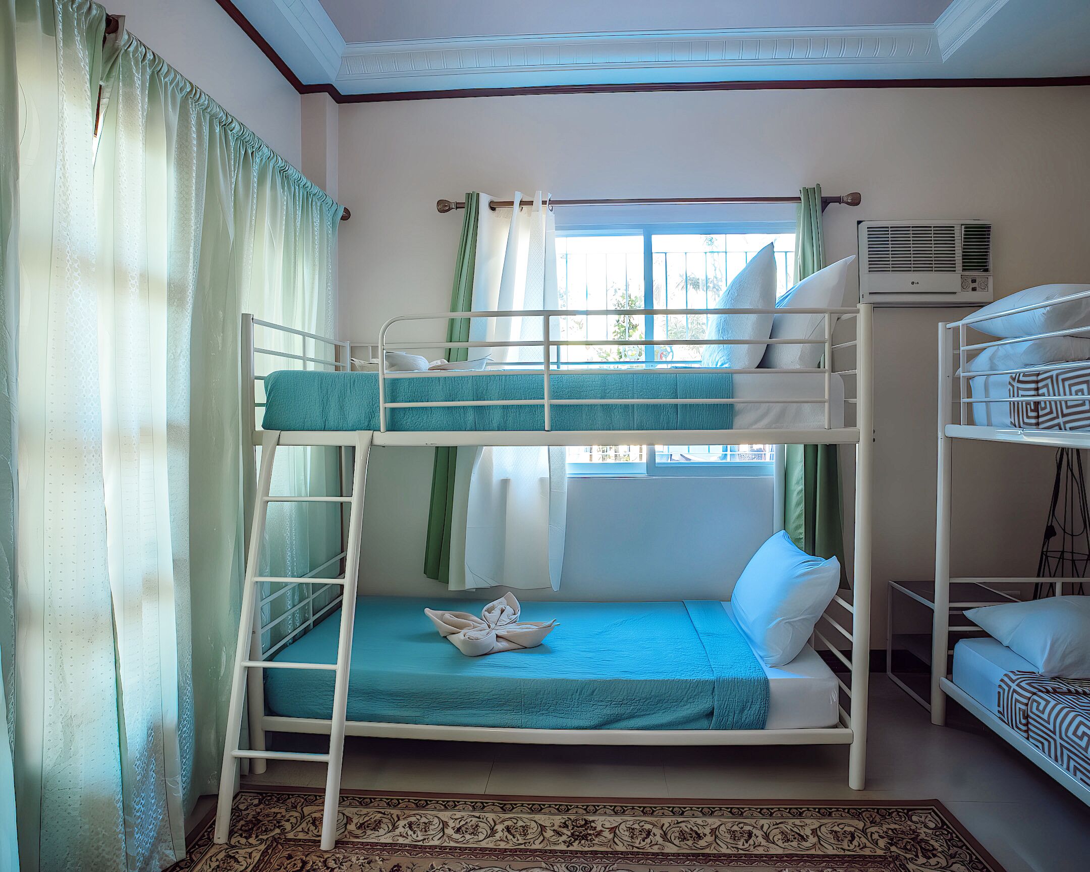 A bunk bed room with a window, curtains, and a patterned rug.