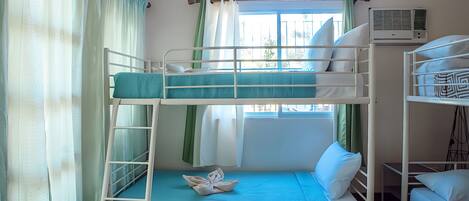 A bunk bed room with a window, curtains, and a patterned rug.