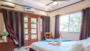 A hotel room with a bed, a desk, a chair, a ceiling fan, and a window with curtains. - Spacious 5-bedroom Panglao Home with FREE transfers, Infinity Pool, WiFi, & A/C (Panglao)