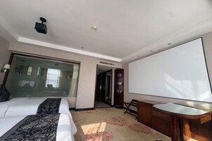 Una habitación de hotel con cama, escritorio, ventana grande y puerta que da a otra habitación.