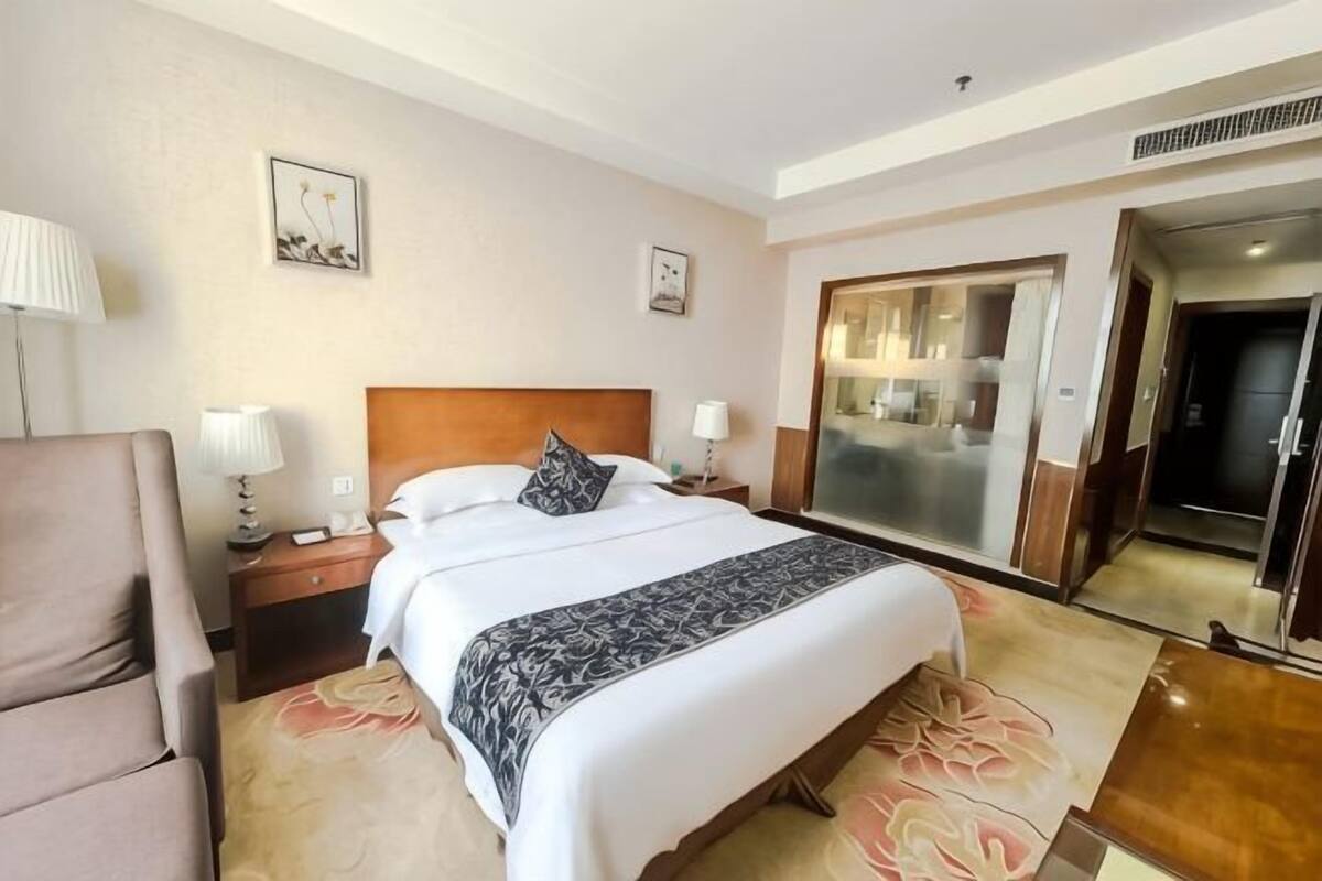 Une chambre d’hôtel avec un grand lit, une chaise, un bureau et un miroir.