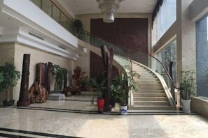 Un hall d’entrée spacieux, agrémenté d’un escalier en colimaçon, de plantes en pot et d’un grand lustre.